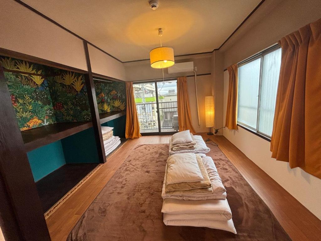 a room with three beds in it with windows at 777 Takamatsu Guest House in Takamatsu