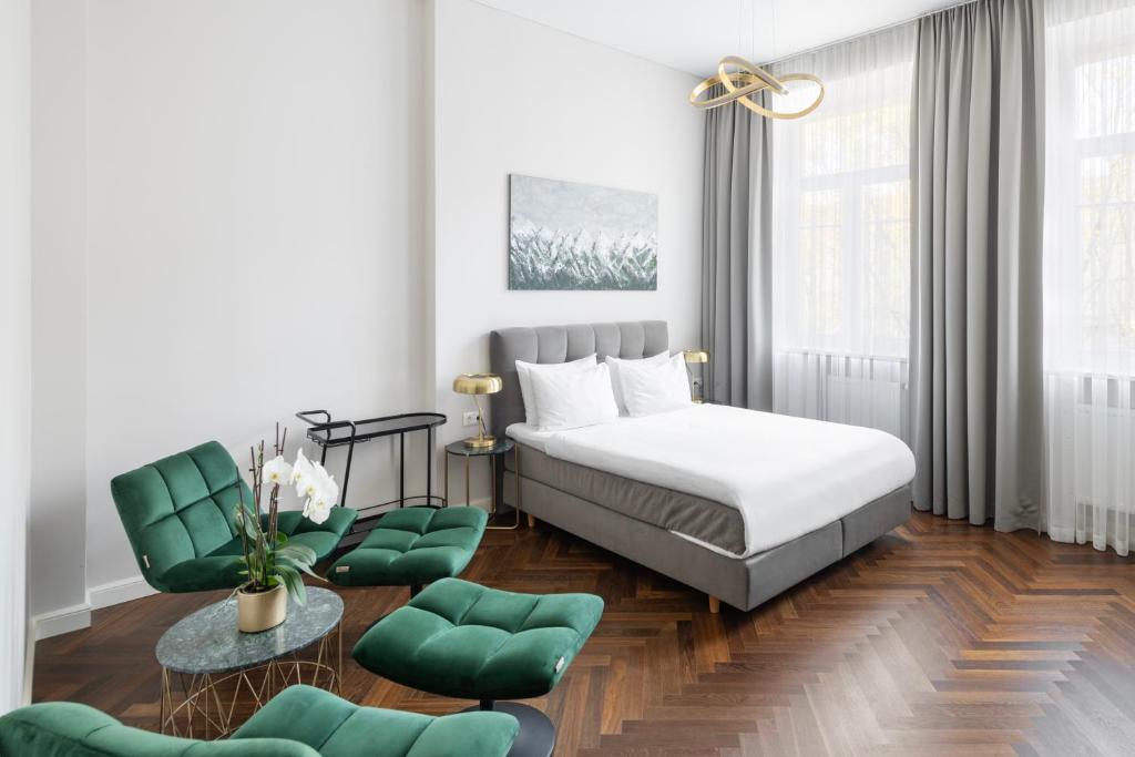 a bedroom with a bed and two green chairs at St Casimir Apartments in Vilnius