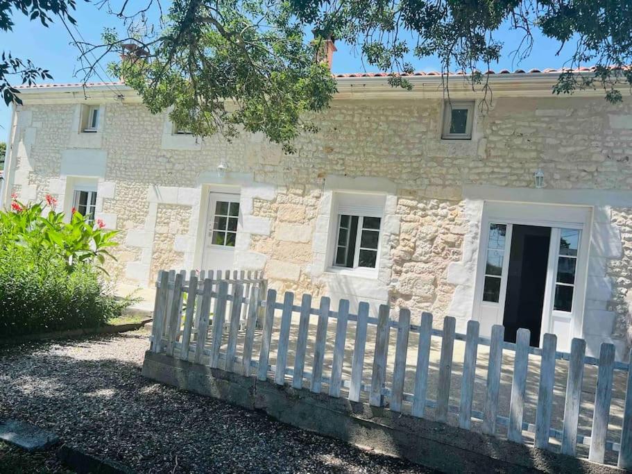 einen weißen Zaun vor einem Steinhaus in der Unterkunft Maison très agréable et familiale Saintes Royan in La Jard