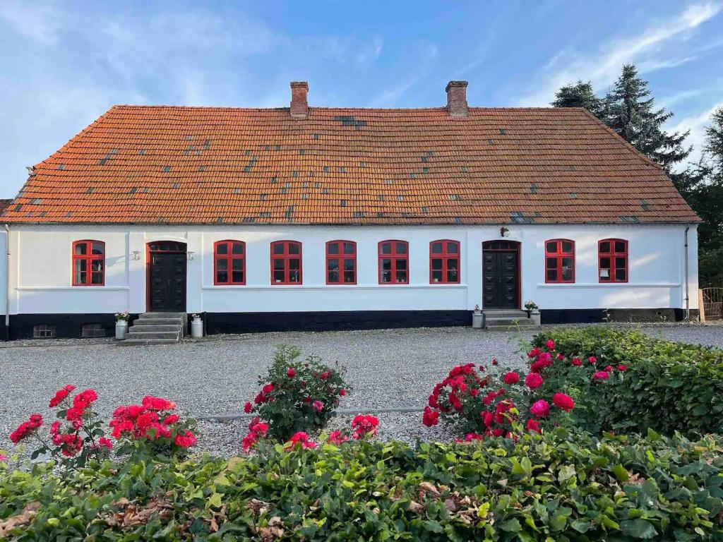 uma casa branca com janelas vermelhas e flores em Country Idyll With Wilderness Bath And Sauna, em Haderslev