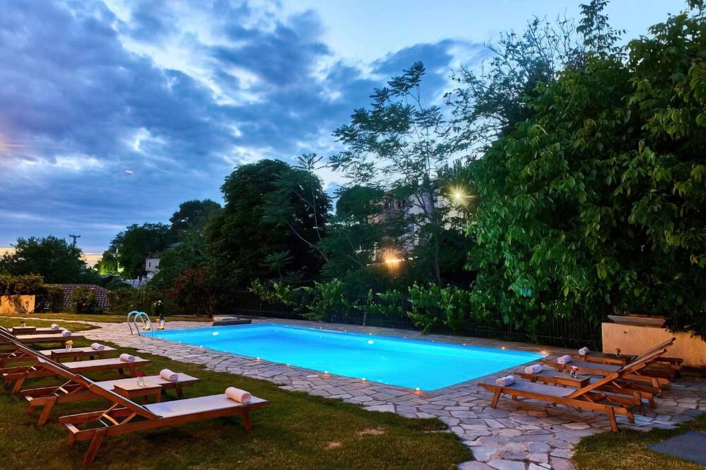 a swimming pool with chaise lounge chairs and a group ofermott at Triantafillies Traditional Hotel in Portaria