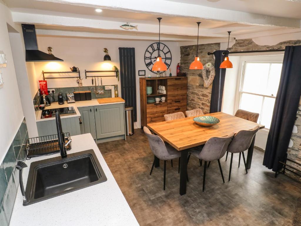 een keuken en eetkamer met een houten tafel en stoelen bij Winterbrook Cottage in St Austell
