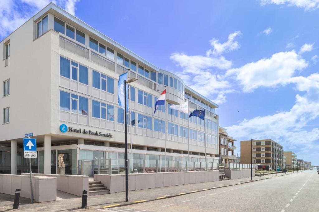 un bâtiment avec des drapeaux sur son côté dans l'établissement Hotel de Baak Seaside, à Noordwijk aan Zee