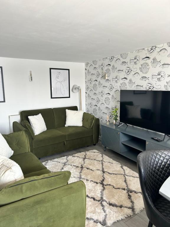 ein Wohnzimmer mit einem grünen Sofa und einem Flachbild-TV in der Unterkunft Sea view apartment on Poole Quay overlooking Sandbanks in Poole