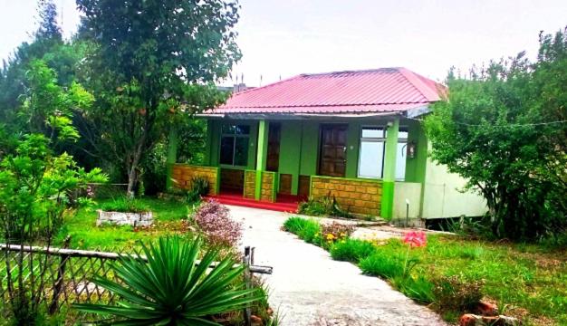 a small house with a red roof in a garden at Abode Me Me Ai Haven in Cherrapunji