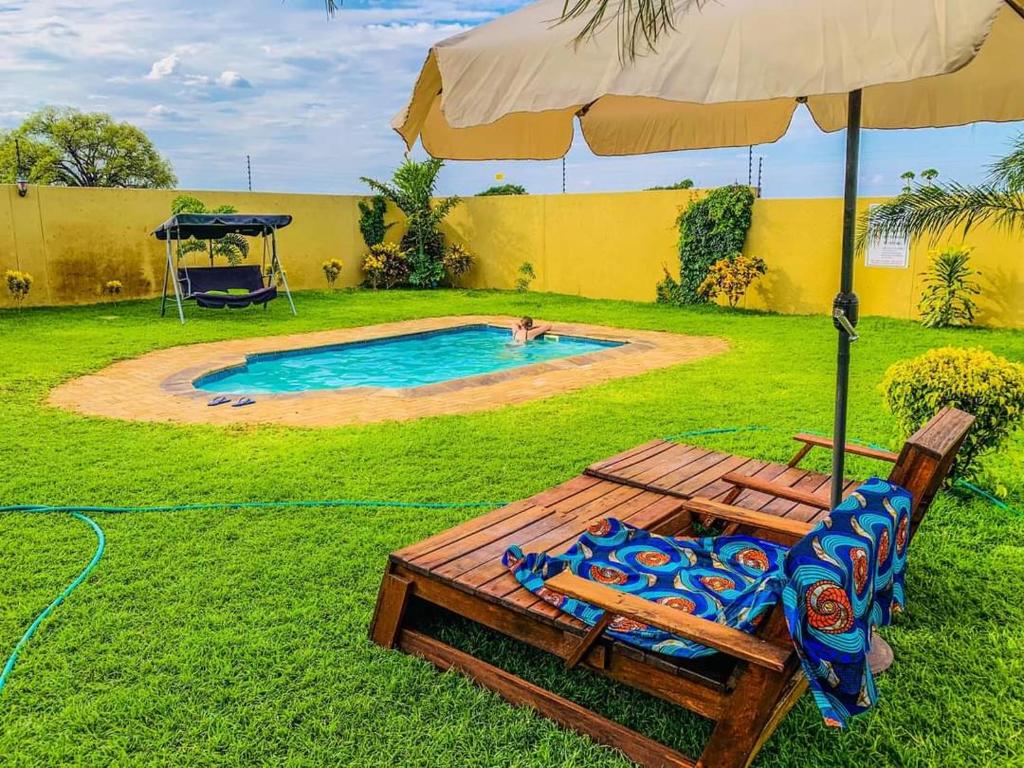 - une piscine avec un parasol, une chaise et une balançoire dans l'établissement Siruwo Guest House, 