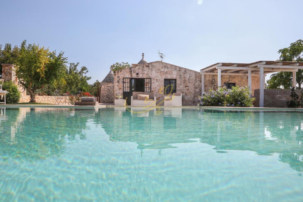 una gran piscina de agua con una casa en el fondo en Trulli Dimore - Trulli della Lama, en Castellana Grotte