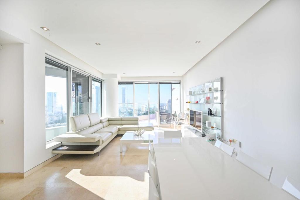 een woonkamer met witte meubels en grote ramen bij Park Tzameret 3BR Panoramic by HolyGuest in Tel Aviv