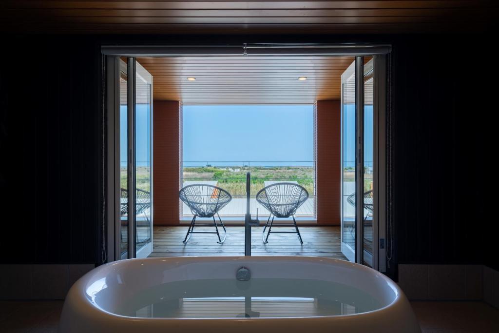 a bath tub in a room with a balcony with chairs at THE SECOND Chousei Beach Village in Jōnouchi