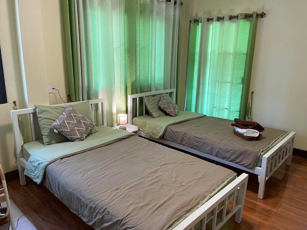 2 camas en una habitación con cortinas verdes en บ้านเรา แอท น่าน, en Nan