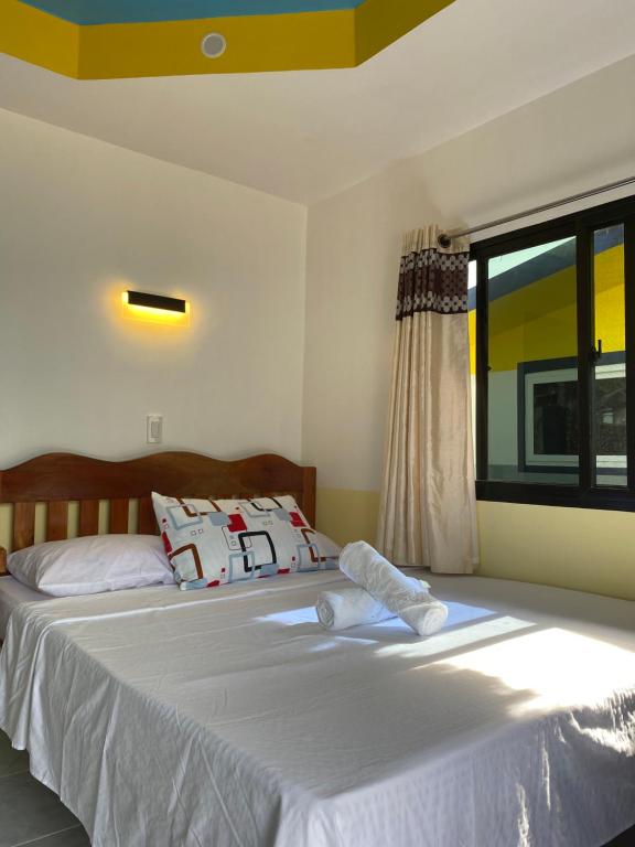 a bedroom with a bed with white sheets and a window at Residencia Gemma in Siquijor