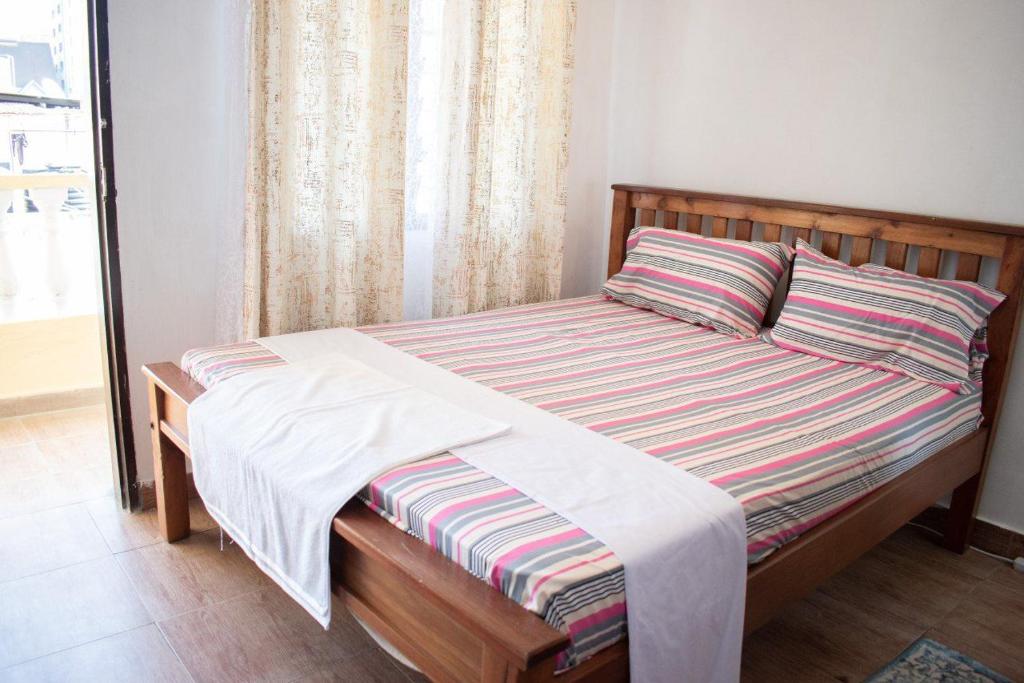 un letto con una coperta a righe e una finestra di Gee's Neat Apartment in Mombasa CBD / Parking 2 a Mombasa