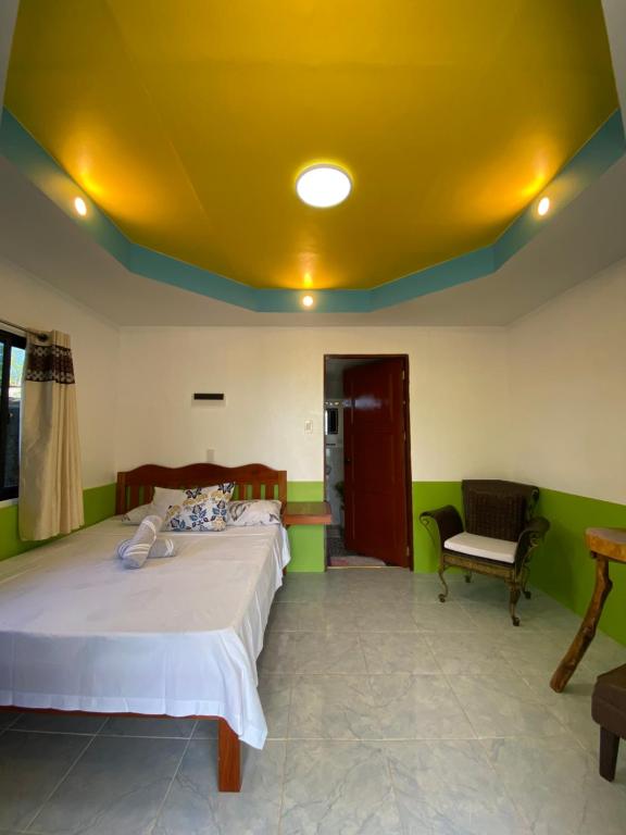 a bedroom with a bed and a yellow ceiling at Residencia Gemma in Siquijor