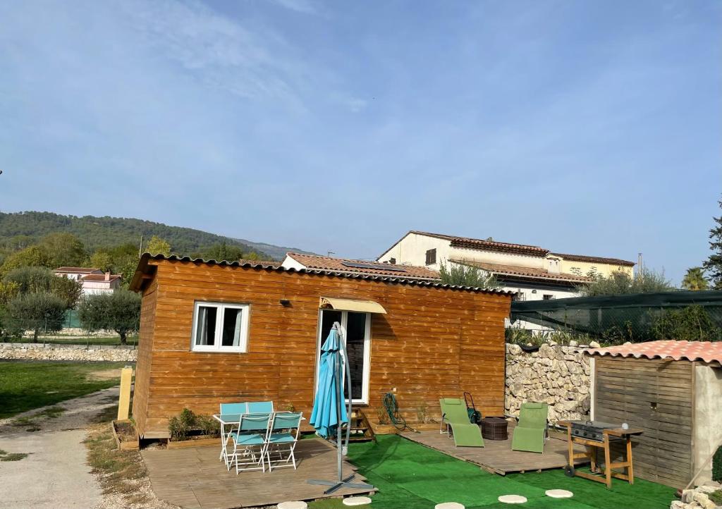 une petite maison en briques avec des chaises et un parasol dans l'établissement Un instant de bonheur, à Grasse