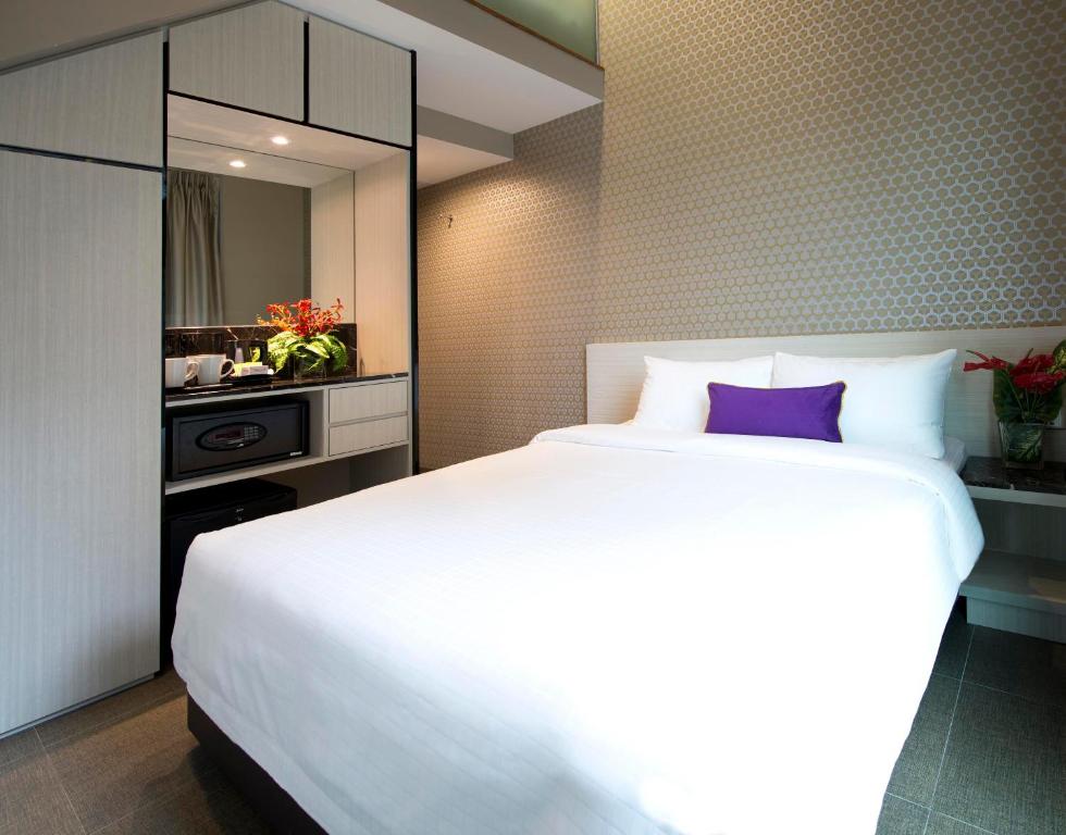 a bedroom with a large white bed with a purple pillow at V Hotel Bencoolen in Singapore