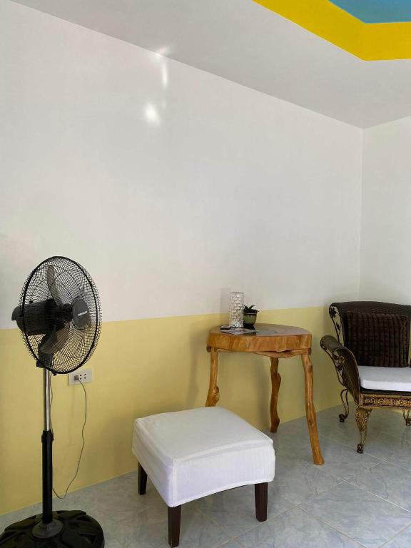 a room with a fan and a table and a chair at Residencia Gemma in Siquijor