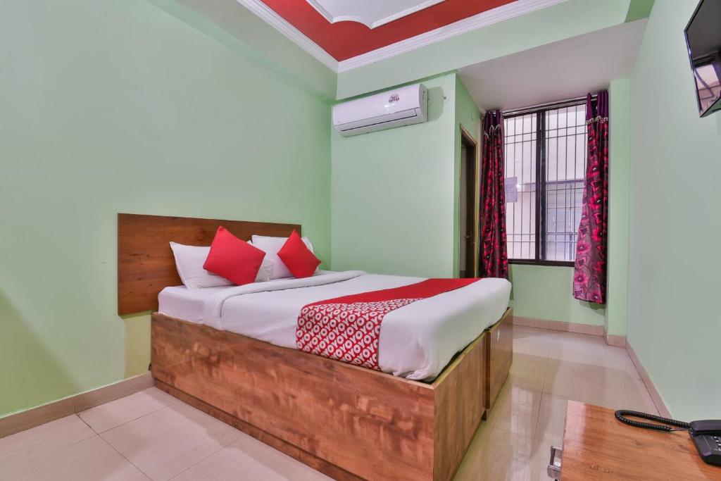 1 dormitorio con 1 cama grande con almohadas rojas en OYO Hotel Happy Journey, en Dīgha