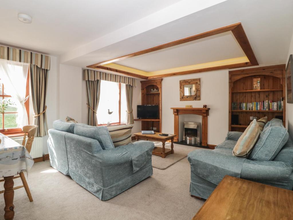 Una sala de estar con dos sillas azules y una chimenea. en Whidbey Luxury Apartment, en Plymouth