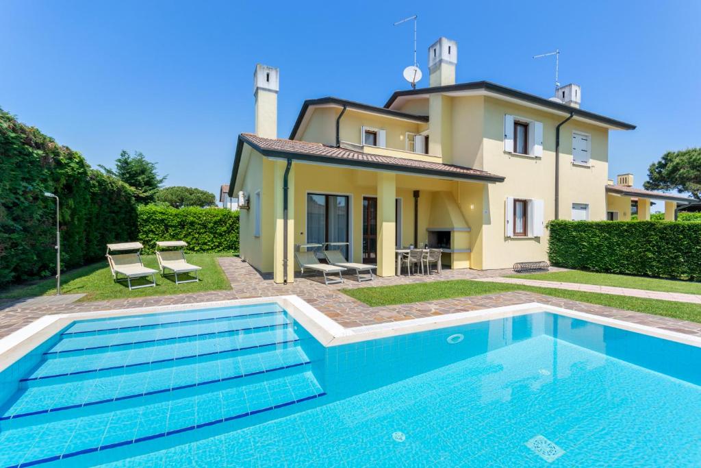 a villa with a swimming pool in front of a house at Isola di Albarella in Isola Albarella