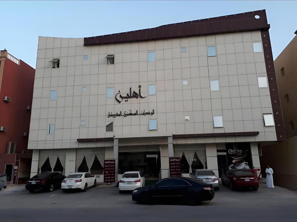 a building with cars parked in a parking lot at Ahlin Suites 1 By Khaymat Alyarmouk in Riyadh