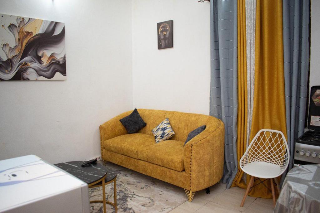 - un salon avec un canapé jaune et une chaise dans l'établissement Gee's Neat Apartment in Mombasa CBD-Parking, à Mombasa