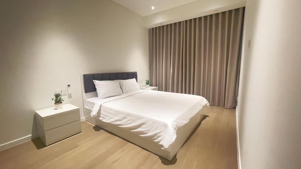 um quarto com uma cama branca e uma janela em The Opera Residence Luxury Apartment em Ho Chi Minh