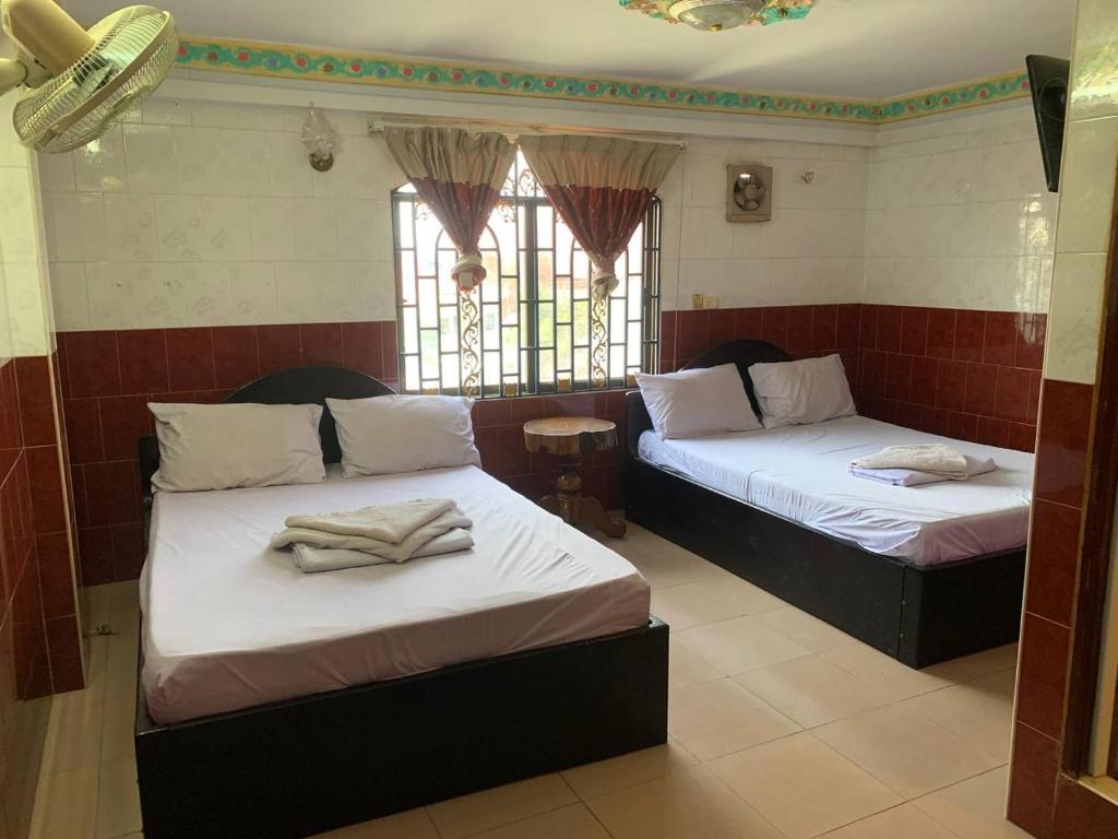 Duas camas num quarto com janelas em Ditar Guest House S em Battambang