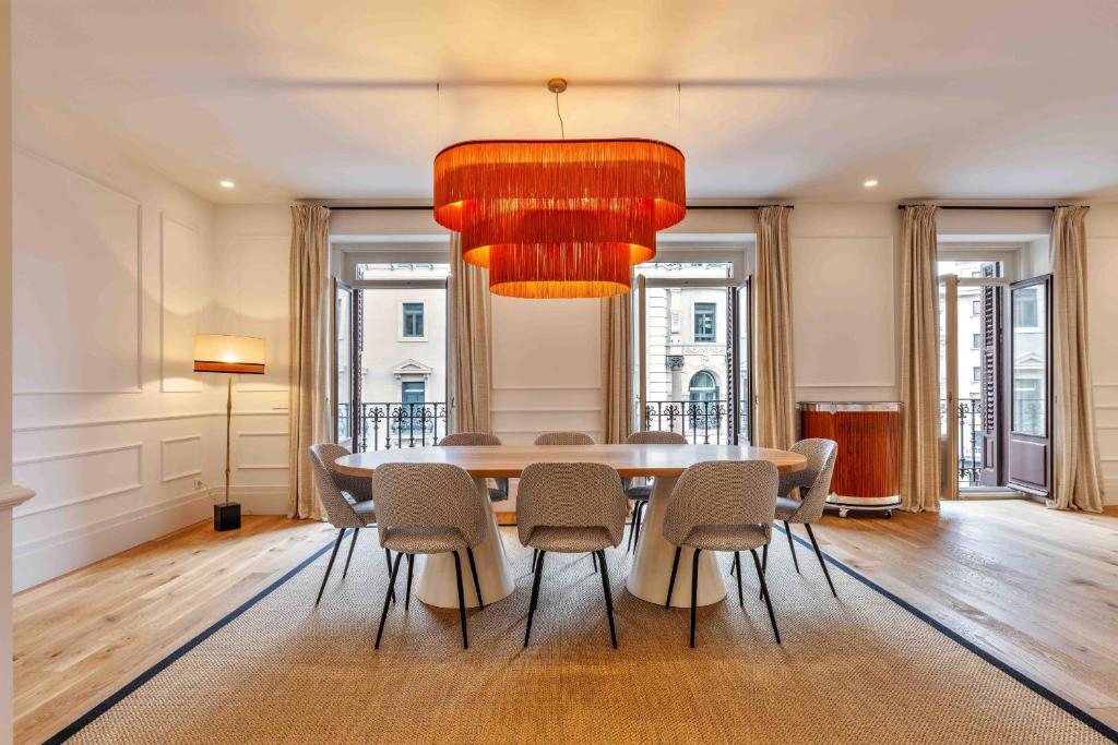una sala da pranzo con tavolo, sedie e lampadario pendente di Apartamento Canalejas Place en Madrid a Madrid