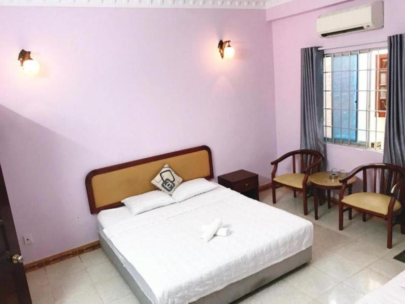 1 dormitorio con 1 cama, mesa y sillas en Nhà Nghỉ Rạng Đông, en Kon Tum