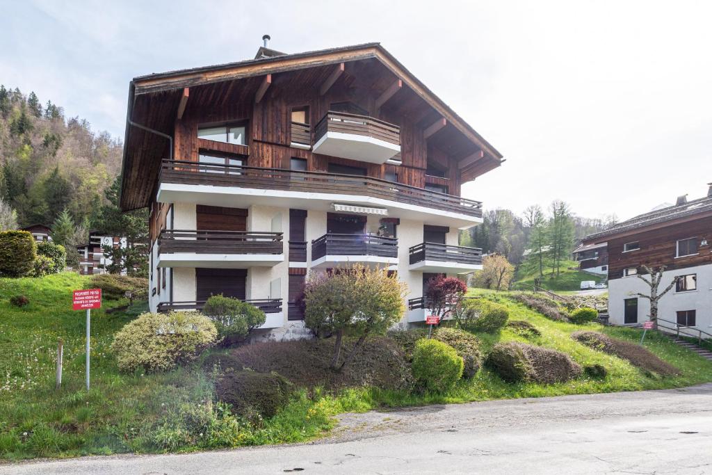 un immeuble d'appartements avec un toit en bois sur une colline dans l'établissement Appartement Les Genevriers, au Grand-Bornand