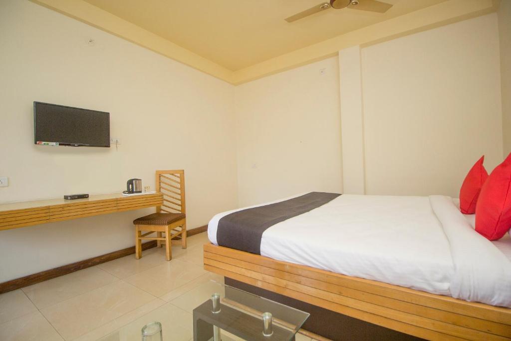 een slaapkamer met een bed en een bureau met een televisie bij Flagship 43145 Mayaban Resort in Ingrāj Bāzār