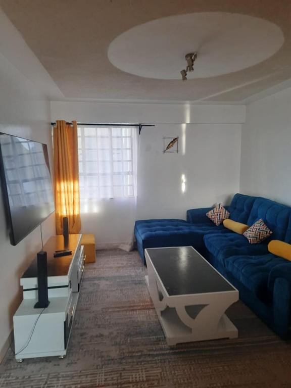 a living room with a blue couch and a table at Lymak 2 bedroom airbnb in Ngong