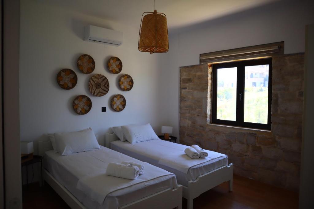 Villa Stefania Dream في Érfoi: سريرين في غرفة مع نافذة وأطباق على الحائط