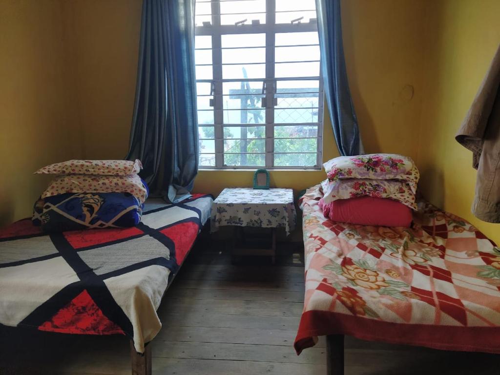 a bedroom with two twin beds and a window at Avi Homestay in Kohīma