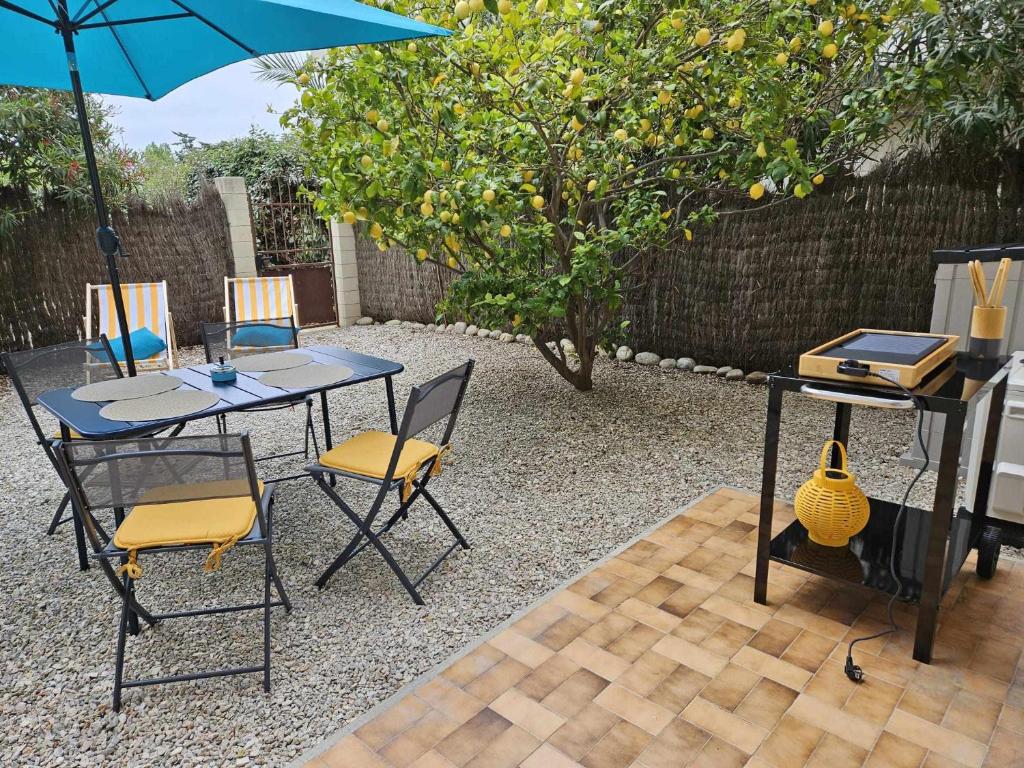 a patio with a table and chairs and an umbrella at Studio calme avec jardin in Canet-en-Roussillon