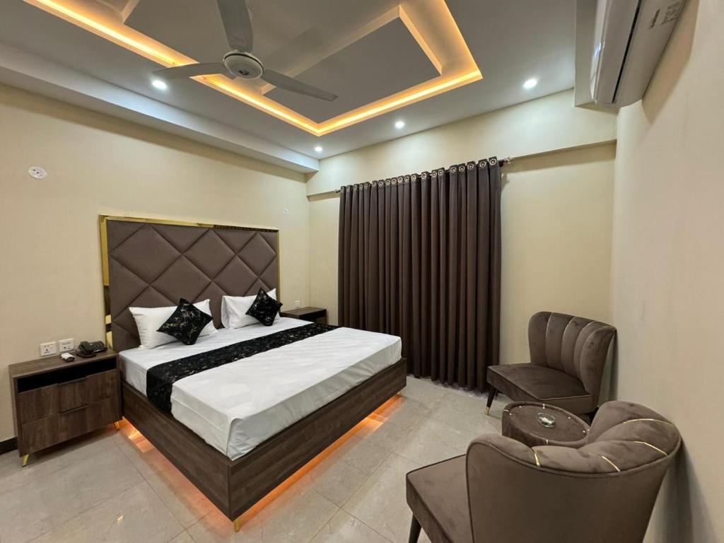 een slaapkamer met een bed, een stoel en een bank bij Gold Pine Hotel Lahore in Lahore