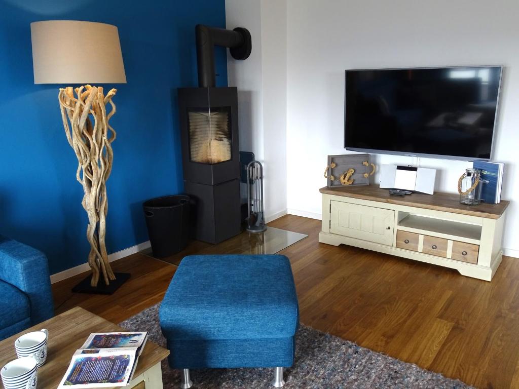a living room with a tv and a blue chair at Gode Wind Quartiere 7 in Dahme