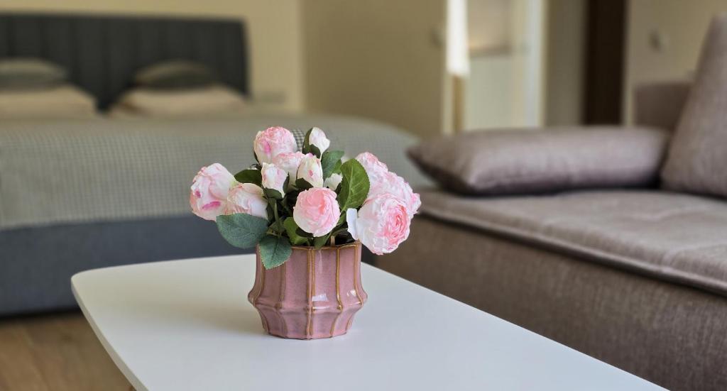 a vase with pink flowers on a table in a living room at Studio Anna in Panevėžys