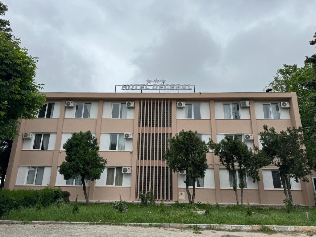 um edifício com árvores em frente em Hotel Decebal Eforie Nord em Eforie Nord