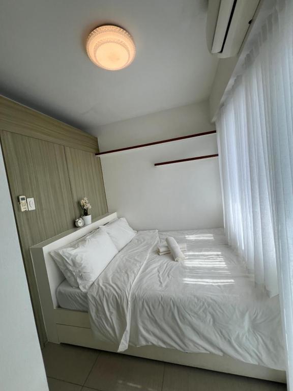 1br Shore Residences Staycation at Royels Place في مانيلا: غرفة نوم بسرير ابيض مع نافذة