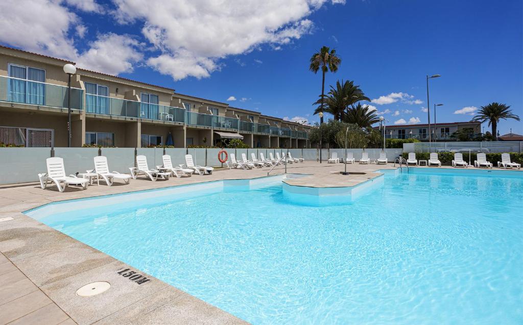 a large swimming pool with chairs and a hotel at Smartr Maspalomas Corinto in Playa del Ingles