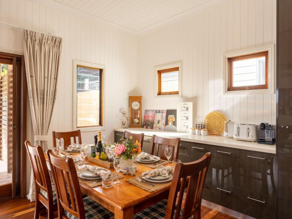 a dining room with a table and a kitchen at 6KM to CBD Convenient 5BR Queenslander Coorparoo in Brisbane