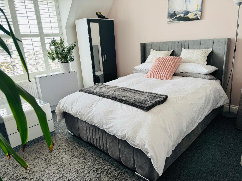 1 dormitorio con cama con almohadas rosas y espejo en Penthouse Suite, Central St Leonards, Sea View, en St. Leonards