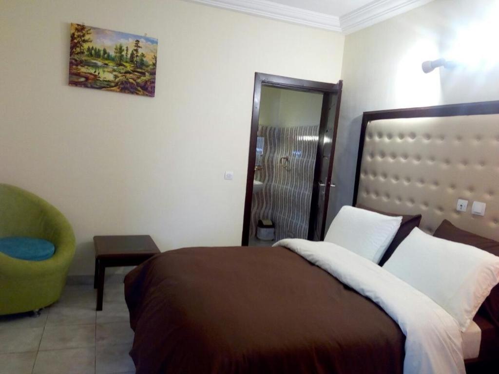 1 dormitorio con 1 cama y 1 silla verde en Hotel Saphir en Abiyán