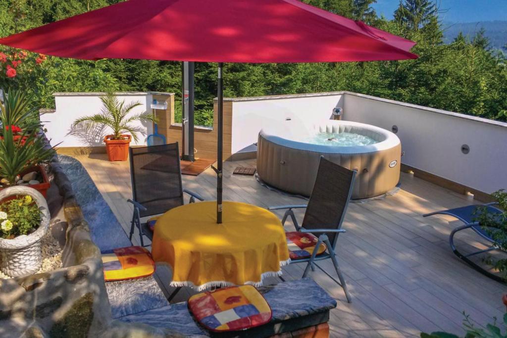a patio with a hot tub and a red umbrella at Bonidesa House With Whirlpool in Ljubno