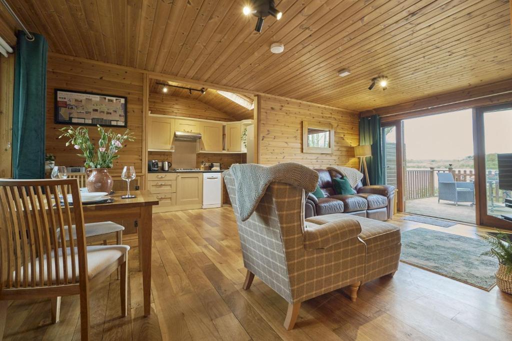 a living room with a couch and a kitchen at Fieldfare Lodge with Hot-tub in Carlisle
