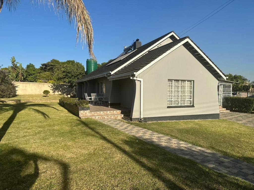 une maison blanche avec un palmier dans la cour dans l'établissement Impeccable 3-Bed House in Harare, à Harare