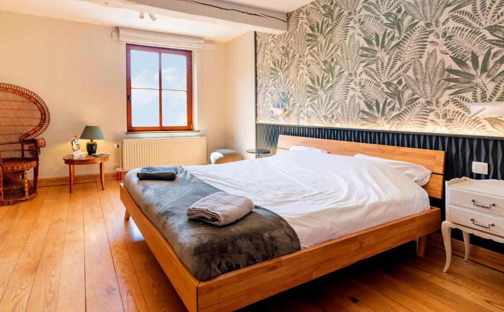 a bedroom with a large bed with a wooden floor at Côté cour, côté source chambre d'hôtes in Chaudfontaine