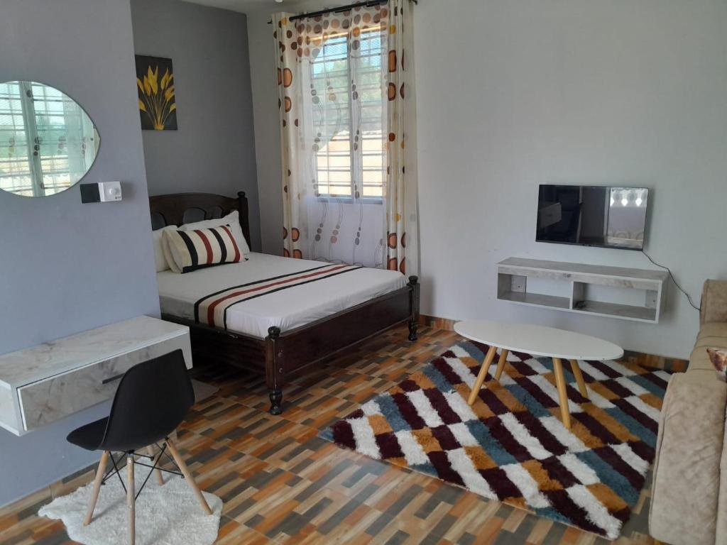 a bedroom with a bed and a table and a tv at Kelly Homes in Kilifi