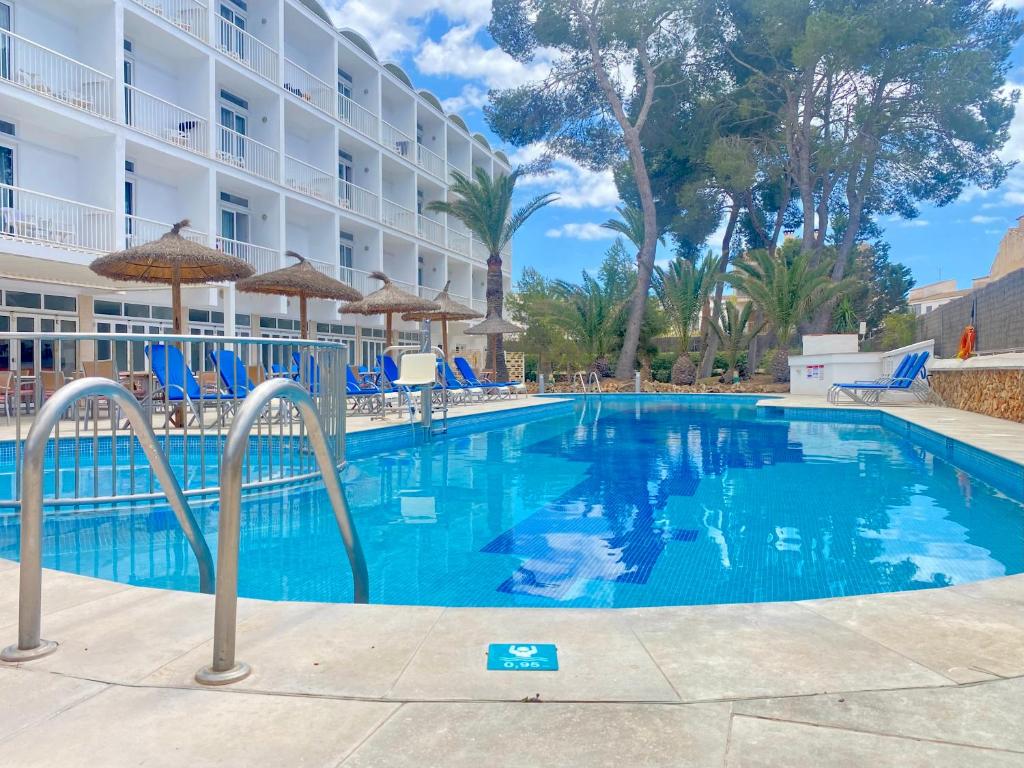 einen Pool in einem Hotel mit Stühlen und Sonnenschirmen in der Unterkunft Hotel Isla de Cabrera in Colonia Sant Jordi